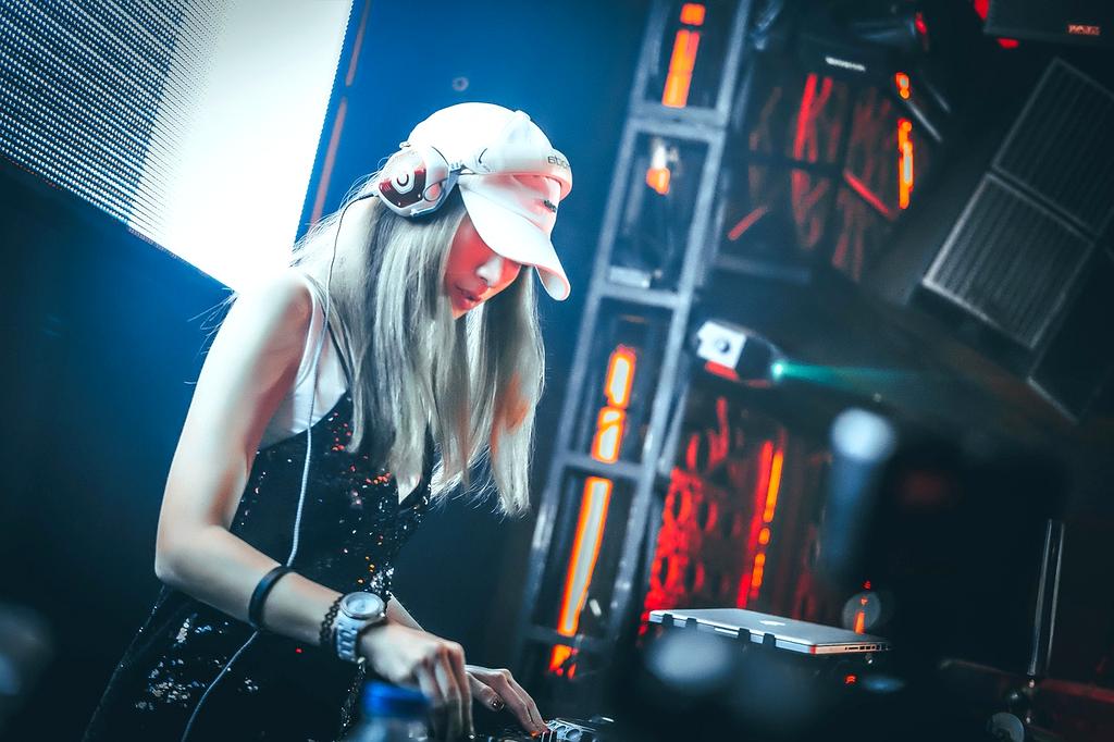 DJ Marco performing electronic music at nightclub with neon lights